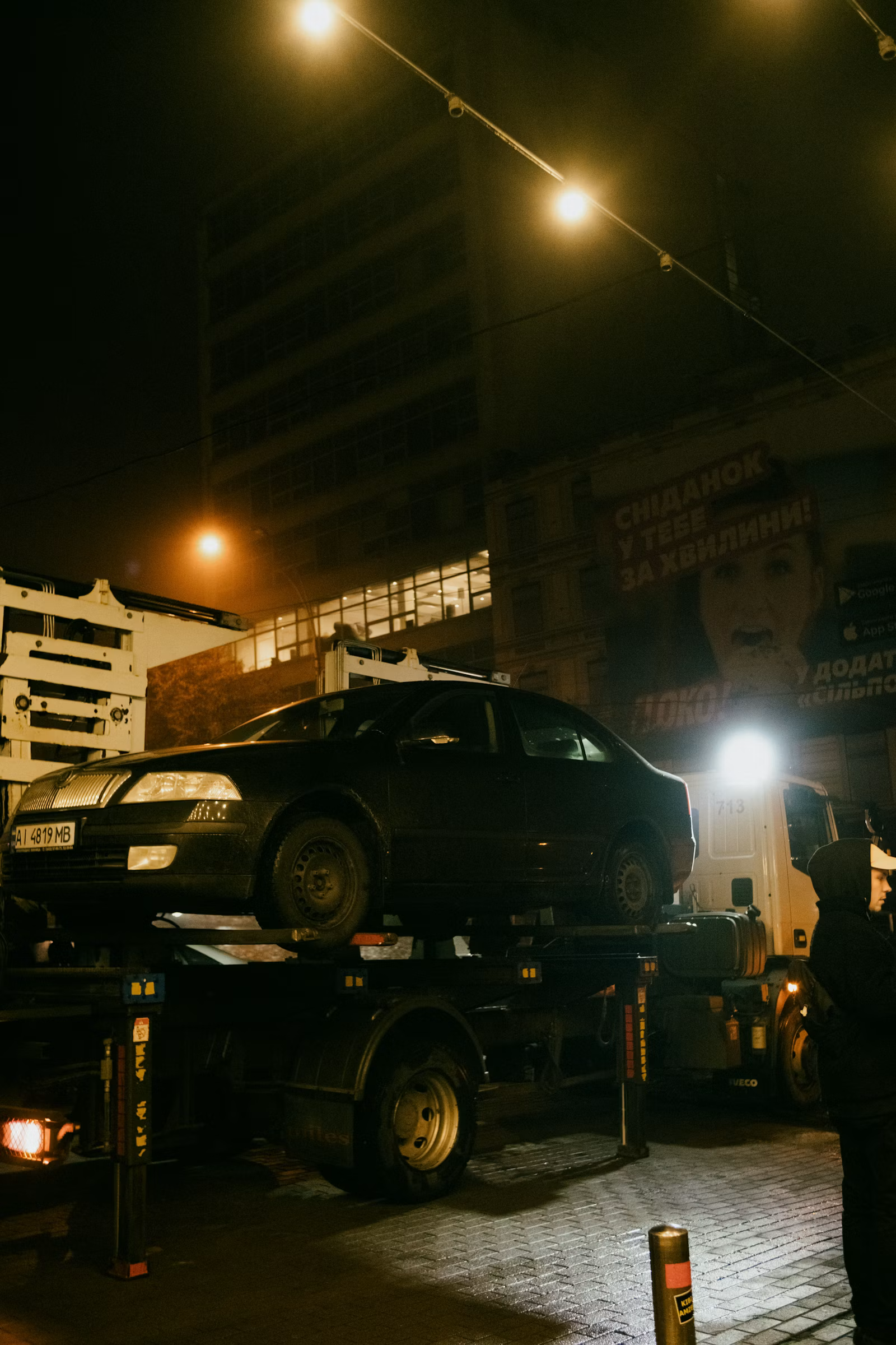 A car loaded on a Mizell's flatbed tow truck at night